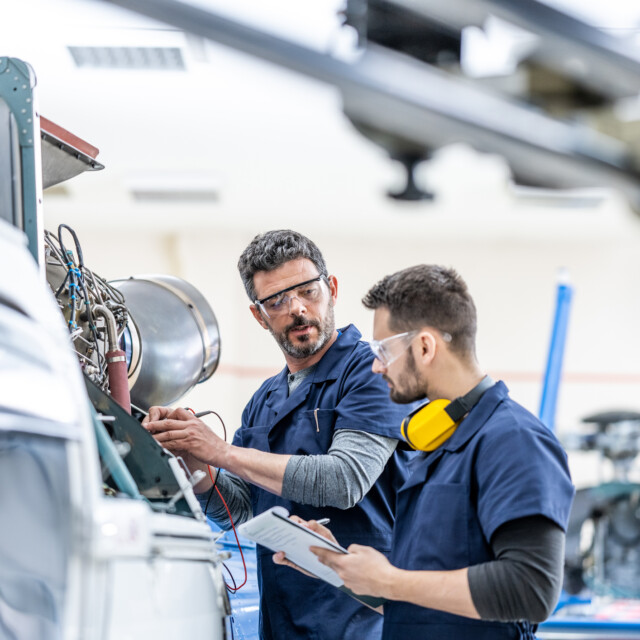 Young Aviation Mechanics Studying To Repair Engine Medium Shot